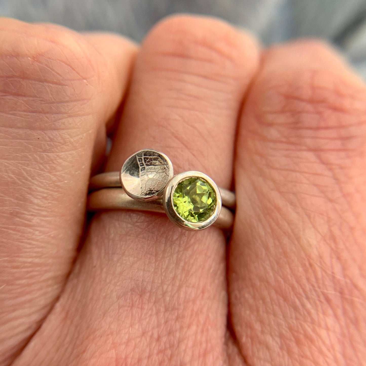 Kate Phipps Jewellery Domed circles ring small leaf skeleton textured silver stacked with scattered trillions peridot and silver ring model photo