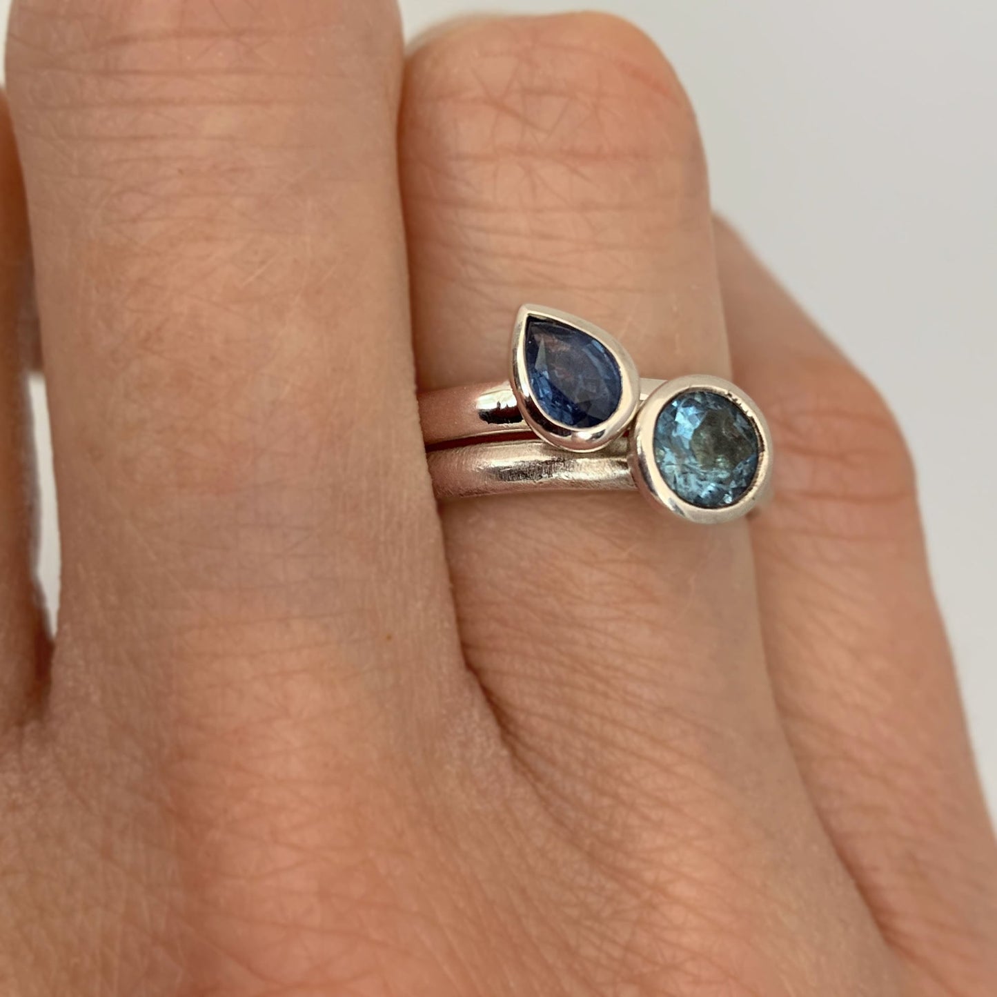 Kate Phipps Jewellery Solitaire ring pear blue sapphire in silver and scattered trillions sky blue topaz and silver model photo
