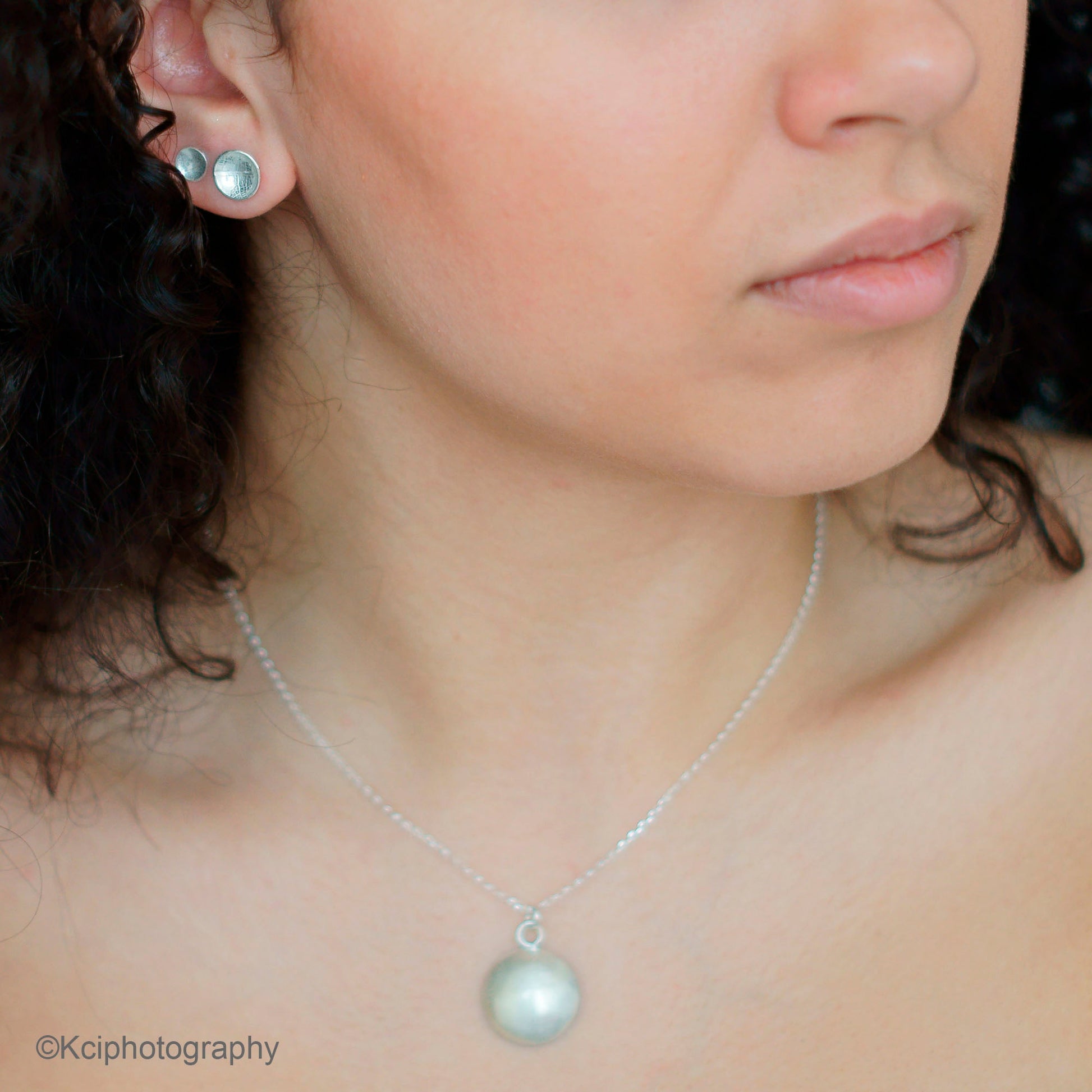 Kate Phipps Jewellery Domed circles set silver stud earrings small and medium and convex side of reversible necklace model photo