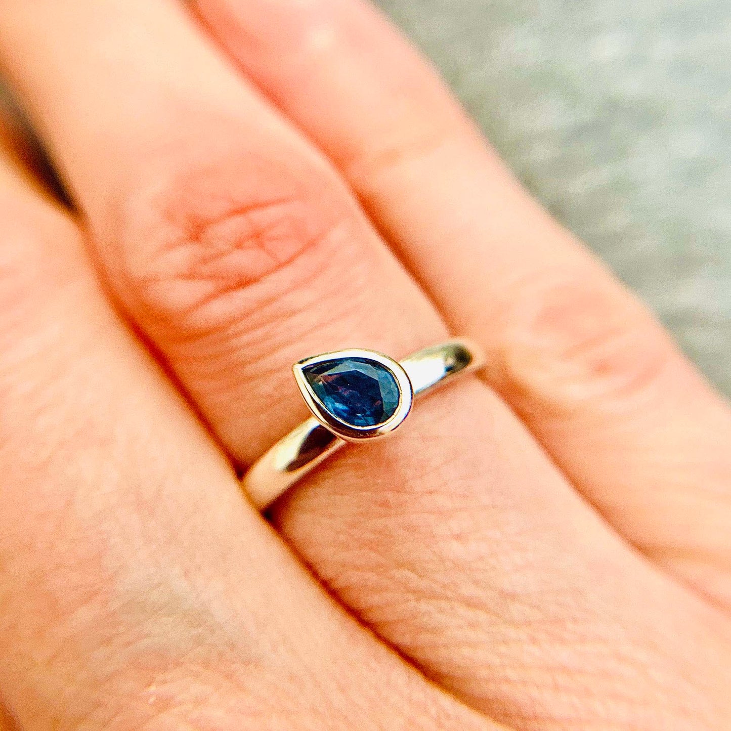 Kate Phipps Jewellery Solitaire pear shaped blue sapphire ring angled set in polished silver model photo