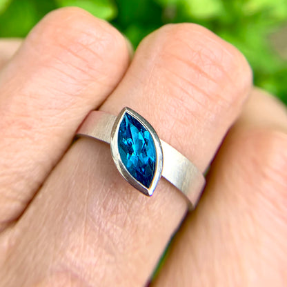 Kate Phipps Jewellery Solitaire ring marquise Swiss blue topaz offset from wide silver band at an angle model photo 1