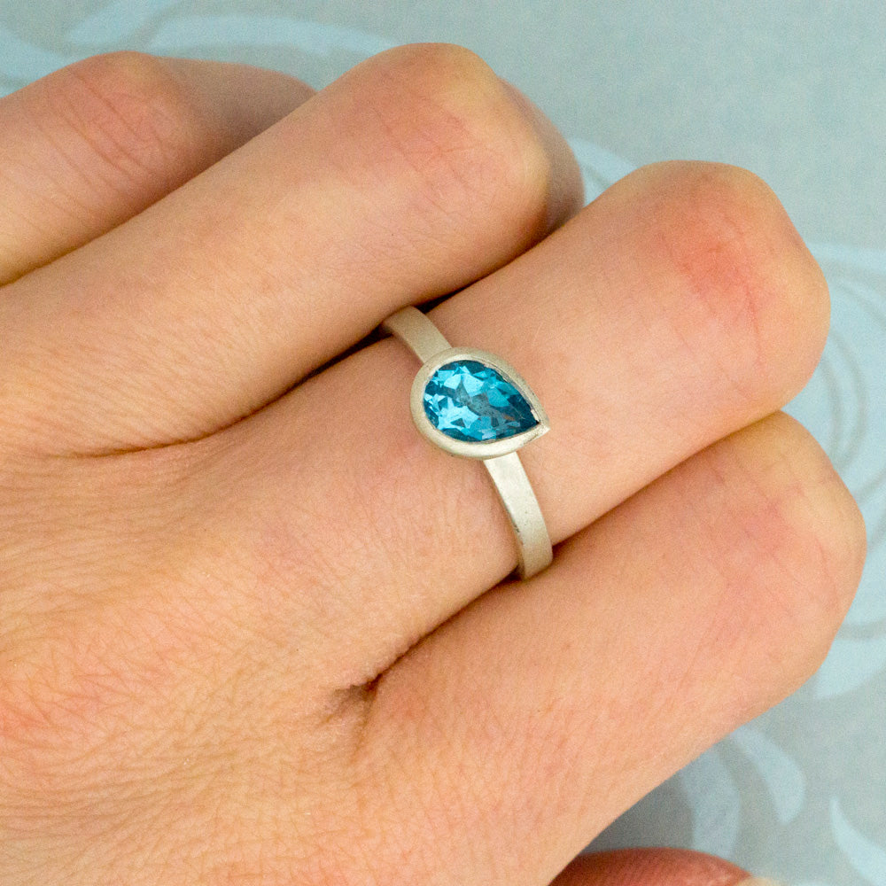 Kate Phipps Jewellery Solitaire ring pear Swiss blue topaz and silver stone at an angle model photo
