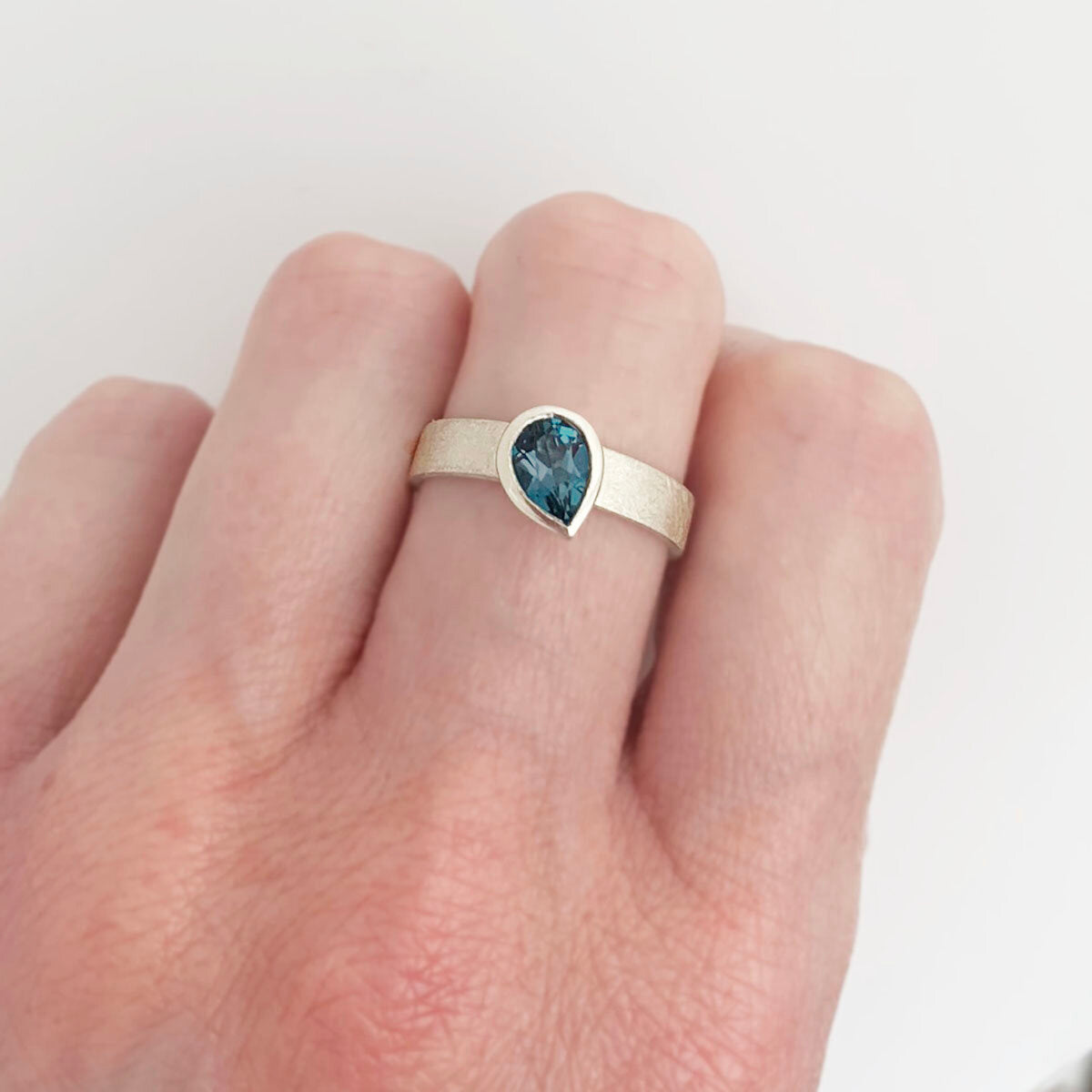 Kate Phipps Jewellery Solitaire ring pear darker London blue topaz offset on silver ring band model photo 3