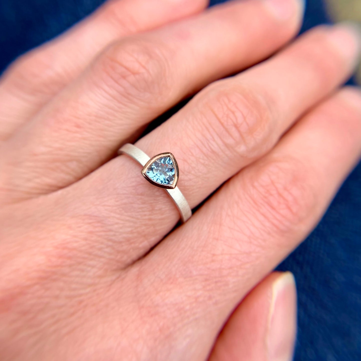 Kate Phipps Jewellery Solitaire ring trillion cut aquamarine set in 9 carat rose gold on a silver ring band model photo 1