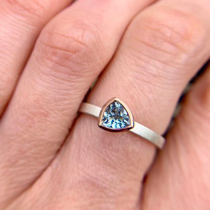Kate Phipps Jewellery Solitaire ring trillion cut aquamarine set in 9 carat rose gold on a silver ring band model photo 2