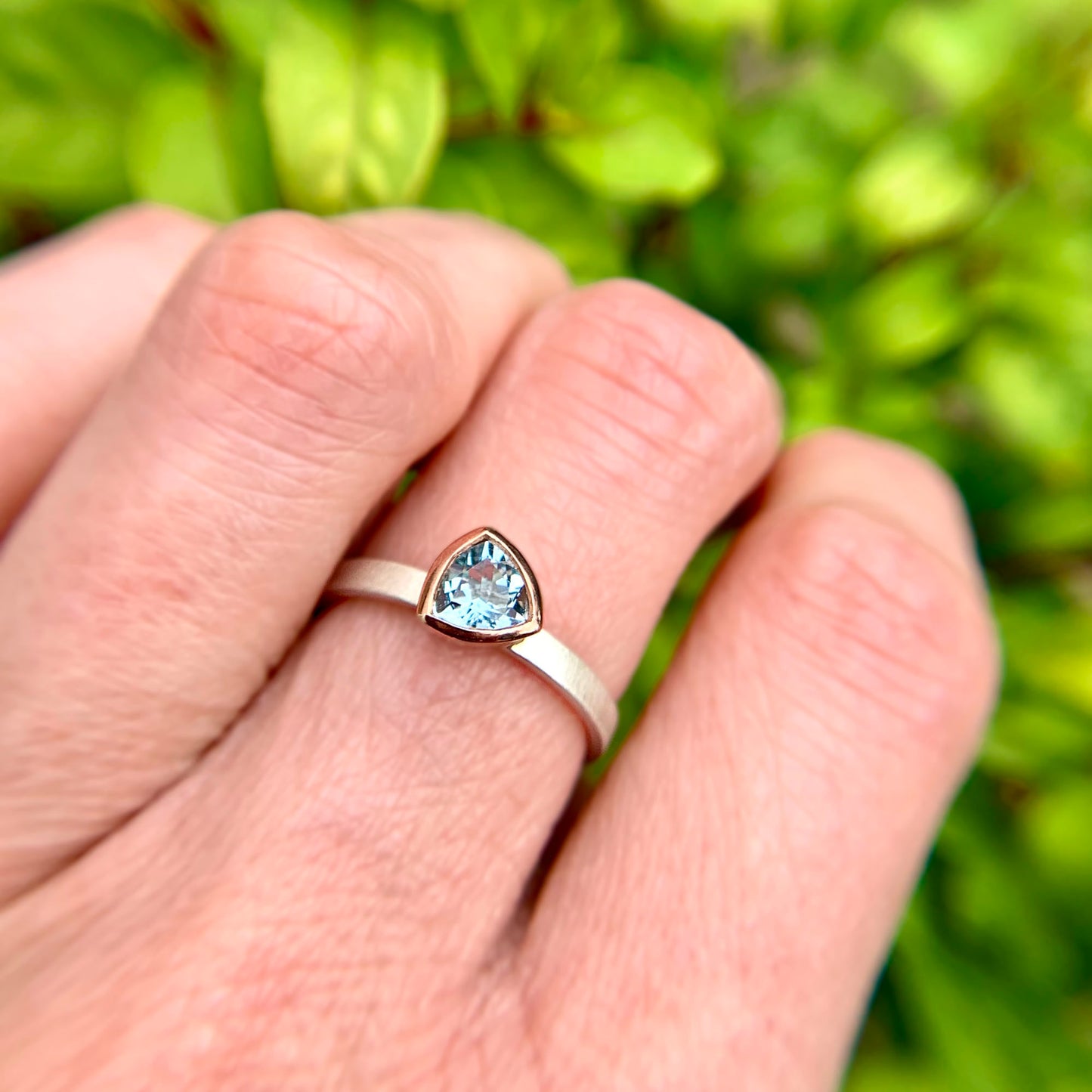 Kate Phipps Jewellery Solitaire ring trillion cut aquamarine set in 9 carat rose gold on a silver ring band model photo 3